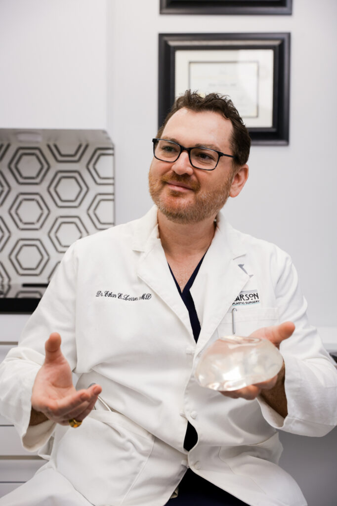 Photo of plastic surgeon holding up an implant to demonstrate options for top surgery near Phoenix